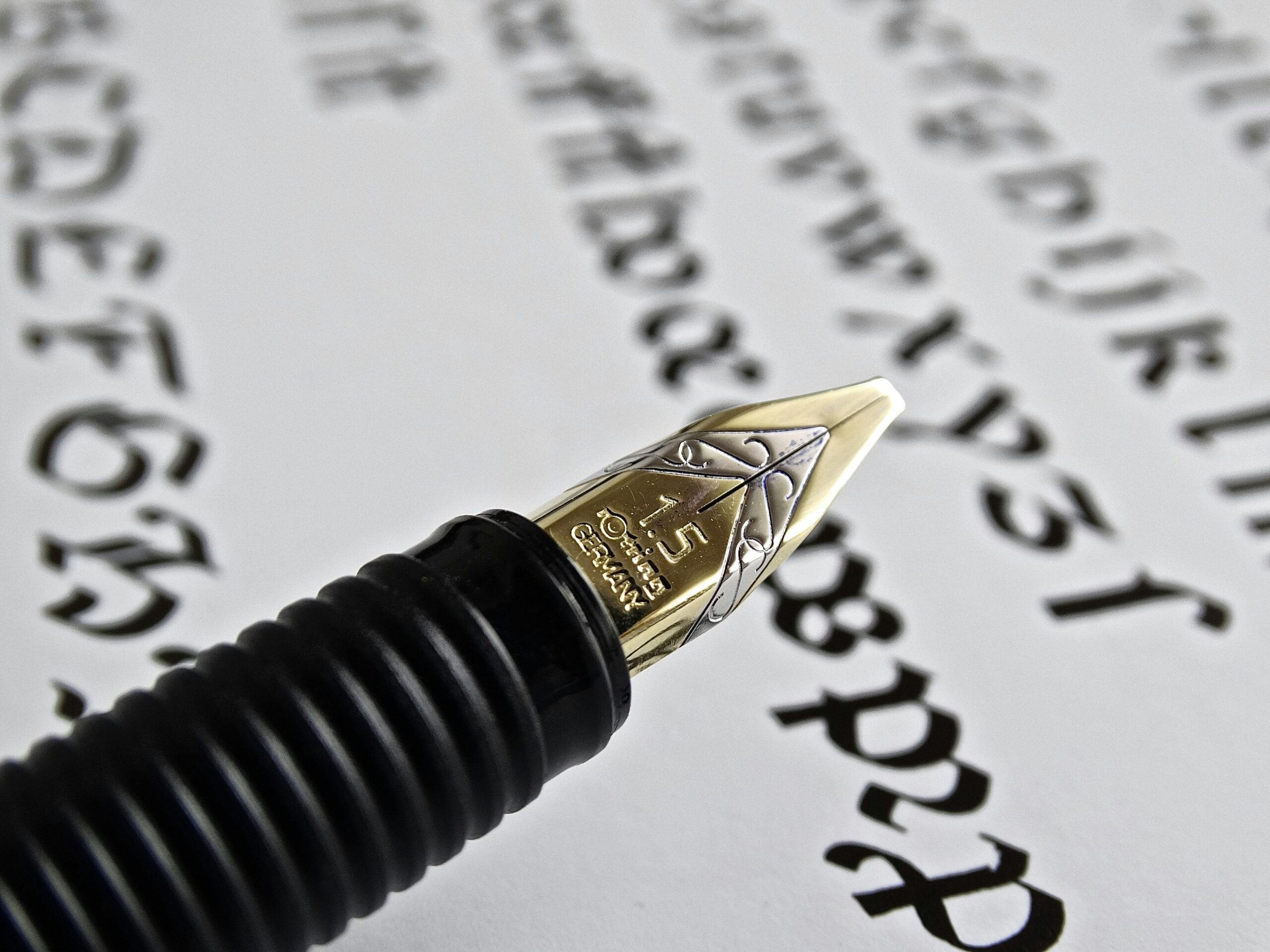 Detailed shot of a gold fountain pen nib on paper with calligraphy.